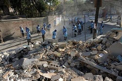 Image of Haitian workers sweep the streets in front of a house that was destroyed by a major earthquake that struck Haiti killing over 200,000 and leaving over a million people homeless. The WHO stopped providing free drugs to private clinics and NGOs in Haiti after reports patients were being charged, potentially dealing a big blow to the already stumbling aid effort.
