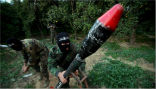 Image of A member of the Popular Resistance Committees in Palestine prepares to launch a rocket into Israel.