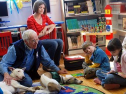 Image of Don Smith and his dog Brasil listen to a young girl read at East Norwalk Library in Conn. The dogs and children participate in the library's 