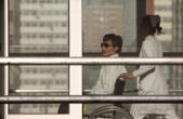 Image of Chen wheeled by a window in the hospital where he is under house arrest