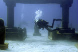 Image of Divers swim through an artificial version of Atlantis in the Caribbean. 