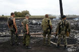 Image of Russian backed separatists stand around wreckage from the downed Malaysian Airlines plane.
