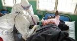 Image of Aid workers in protective clothing treat a woman infected with the Ebola virus.
