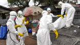 Image of Health workers transport the body of an Ebola victim wrapped in a plastic bag. Ebola victims are burned in the bags they're collected in.