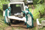 Image of Aid workers in protective gear pick up the bodies of those killed by Ebola in Sierra Leone.
