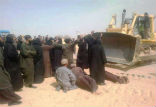 Image of Coptic monks lie before bulldozers as workers chant 