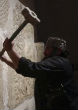 Image of An ISIS member destroys part of an ancient wall in Syria.