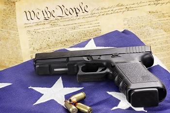 Gun on an American flag with the U.S. Constitution in the background