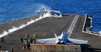 F-18 jets fly from the deck of the USS Carl Vinson.