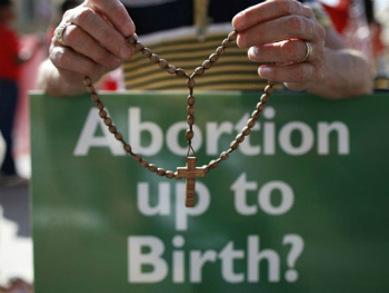 A protestor prays as the BMA debates Measure 50.