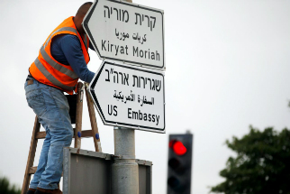 A worker posts signs to direct people to the new U.S. embassy in Jerusalem.
