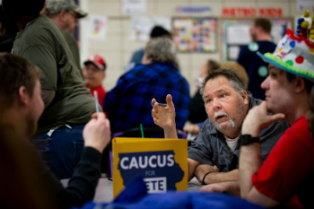 Image of Democrats work to make sense of the situation. Their reporting app failed, forcing many to call for technical support, jamming phone lines and resulting in hours long waits. Directed to use phones and paper ballots instead, the phone lines were once again jammed. The results are taking a long time to verify. 