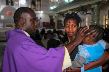 Image of A priest signs the forehead of a child as Catholics take part in the Ash Wednesday celebration at St. Patrick cathedral in Maiduguri Nigeria Feb. 26 2020