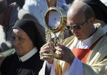 Image of Local priest carries the consecrated host in a procession before about 1000 of the Catholic faithful in Poland