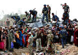 Image of Uzbek refugees crowd around an armoured vehicle with Kyrgyz soldiers in the southern city of Osh while waiting to cross the border into Uzbekistan.