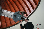 Image of A Jesuit priest looking through the Vatican Observatory telescope. 