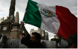 Image of Pemex Gas Station.  Nearby protesters are corralled by police in riot gear, underscoring the intensity of the issue for the Mexican people. 