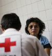Image of A woman waits for a Red Cross worker to provide treatment following a brutal rape and beating. 