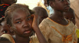 Image of South Sudanese children wait to eat. Food relief is barely trickling in and supplies will run out by the end of May.