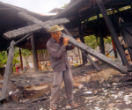 Image of A man removes a charred cross from a burned out church. Christian persecution takes place constantly around the world. 