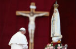Image of Pope Francis kneeling before a statue of Our Lady of Fatima. 
