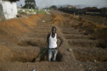 Image of A man digs a grave for Ebola victims during the outbreak in West Africa. The 2014-1026 outbreak was the most serious in history and its global spread was only prevented by swift action by international health officials. 