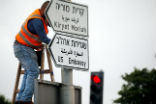 Image of A worker posts signs to direct people to the new U.S. embassy in Jerusalem. 