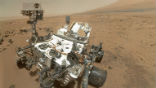 Image of A selfie from the Curiosity rover. Curiosity looks small but is actually the size of a compact car. Fun Fact: Mars is the only planet inhabited entirely by robots. 