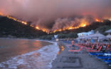 Image of A man takes refuge on a beach in Greece as fires ravage the country.